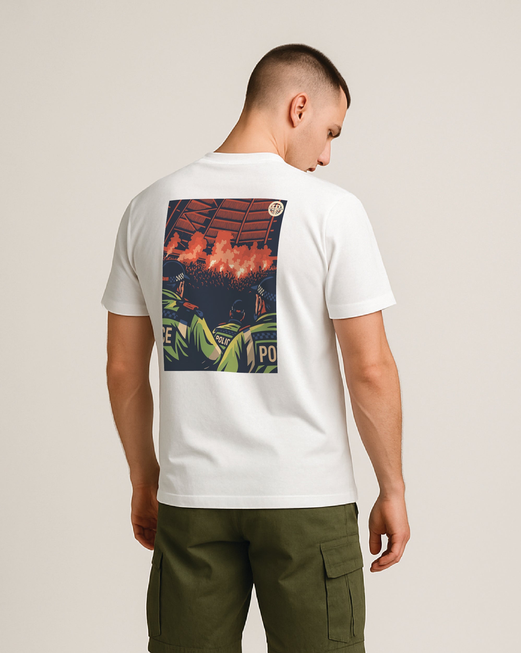 Man wearing a white ultras t-shirt with a colorful pyro show and acab graphic on the back and green shorts against a plain background