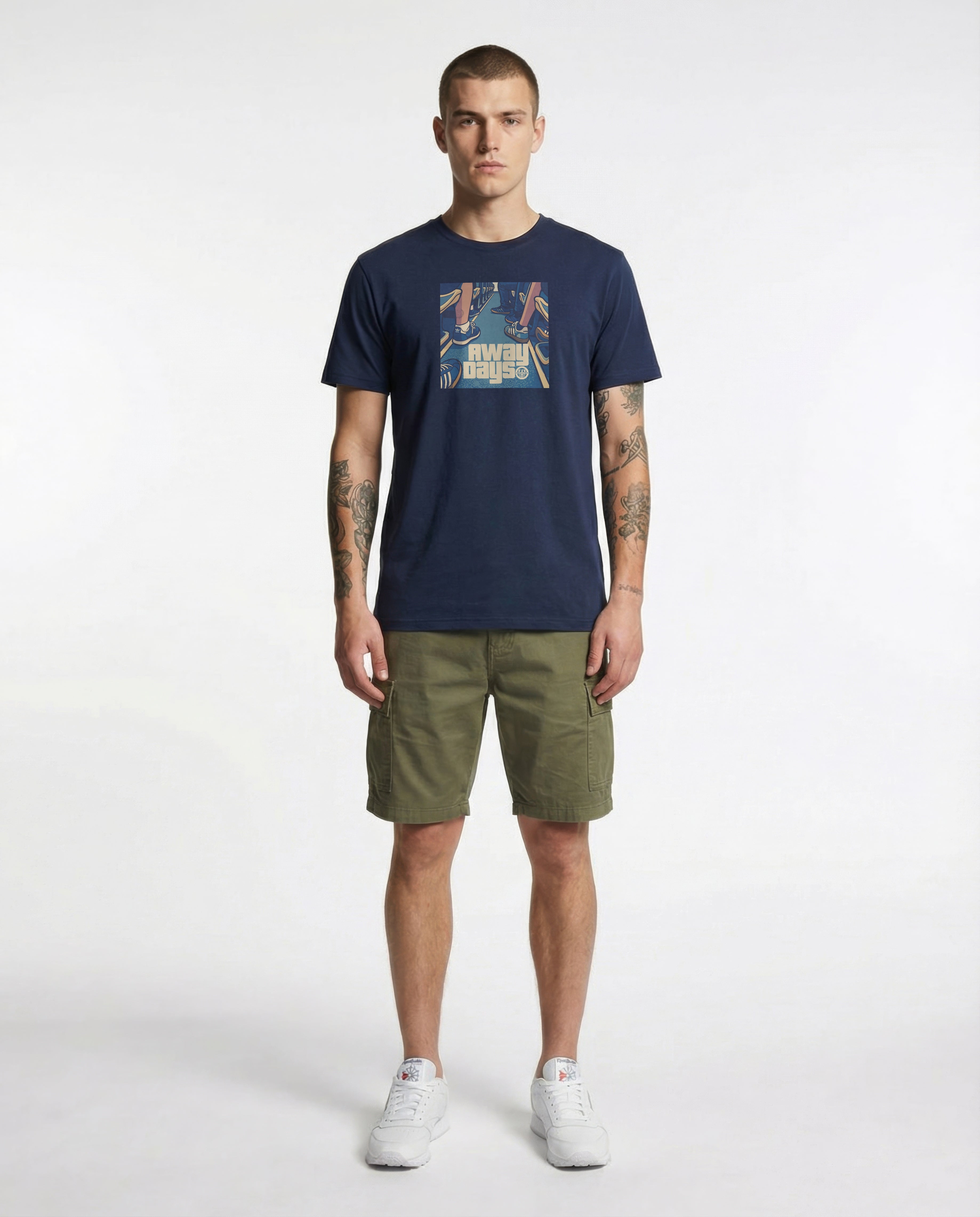 Man wearing a "AWAY DAYS" navy t-shirt with graphic design and green shorts on a white background