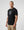Man wearing a black t-shirt with a graphic design on a plain background