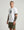 Man wearing a white t-shirt with a graphic design and green shorts on a plain background
