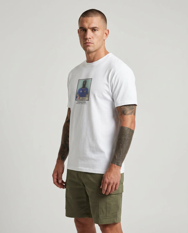 Man wearing a white t-shirt with a graphic design and green shorts on a plain background