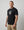Man wearing a black t-shirt with a graphic design on a plain background