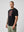 Man wearing a black t-shirt with a graphic design on a plain background