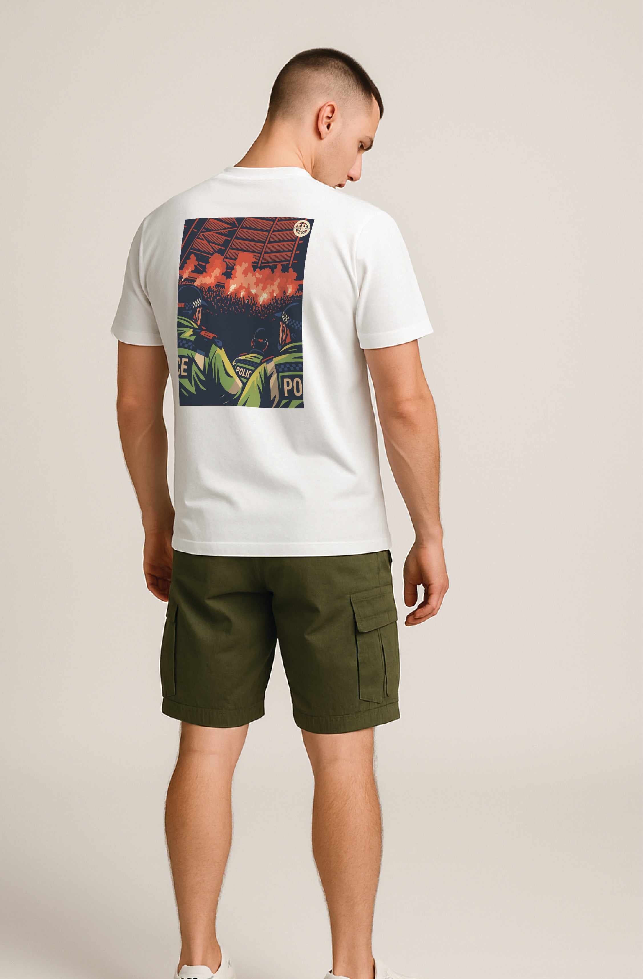 Man wearing a white ultras t-shirt with a colorful pyro show and acab graphic on the back and green shorts against a plain background