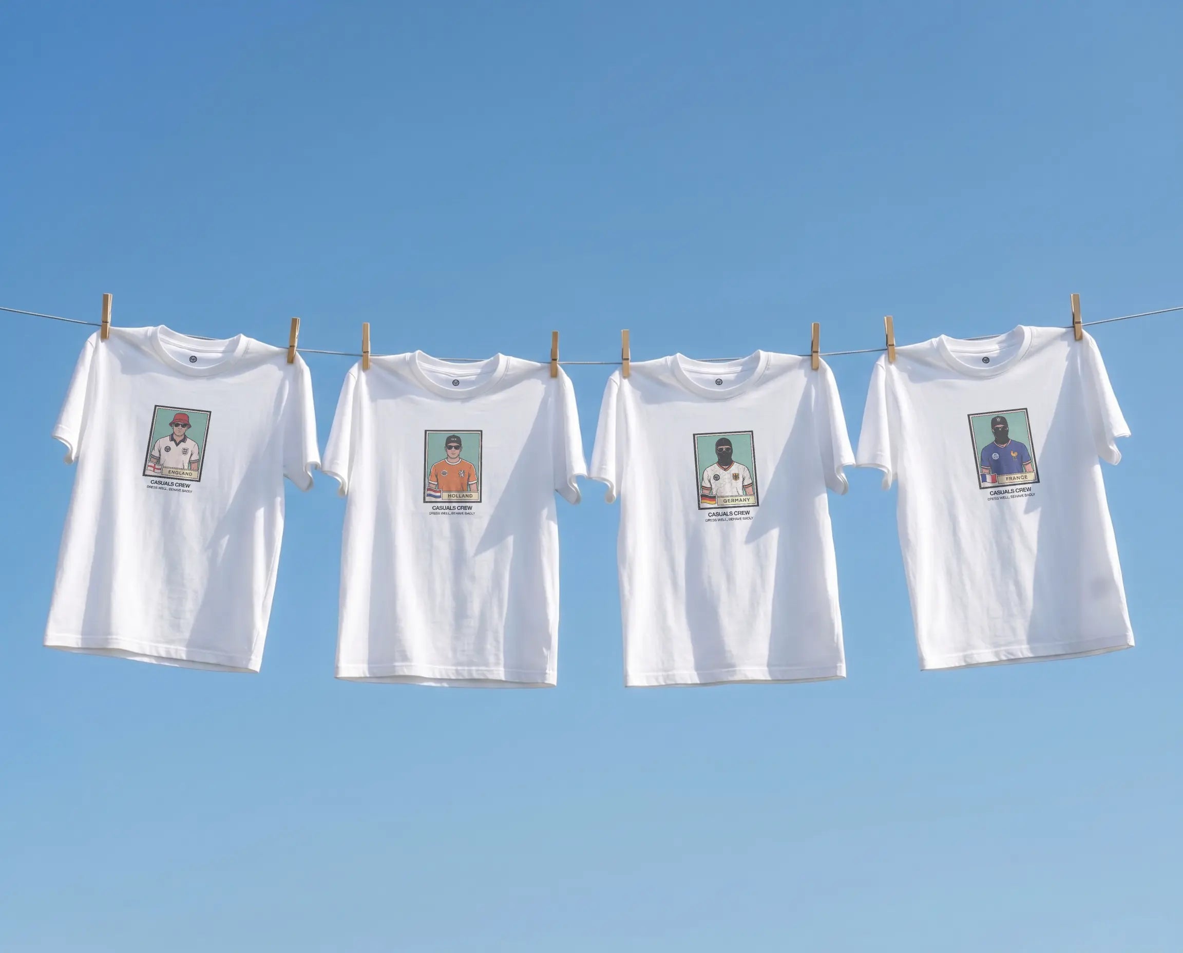 Four white casuals ultras World Cup  t-shirts with printed images on a clothesline against a blue sky.