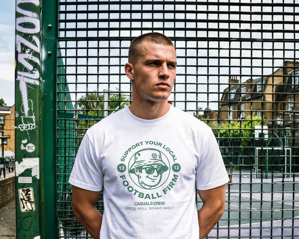 Man wearing a white t-shirt with a graphic design standing in front of a metal fence.